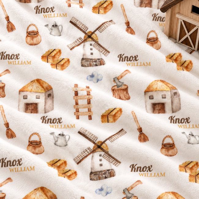 A close-up of a white fabric with a repeating watercolor-style print of rustic farm motifs, including windmills, baskets, huts, axes, brushes, and the text 'Knox William'.