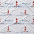 White fabric with a repeating nautical pattern featuring red-and-white lighthouses, blue water, small birds, and the name EMERSON printed in blue.