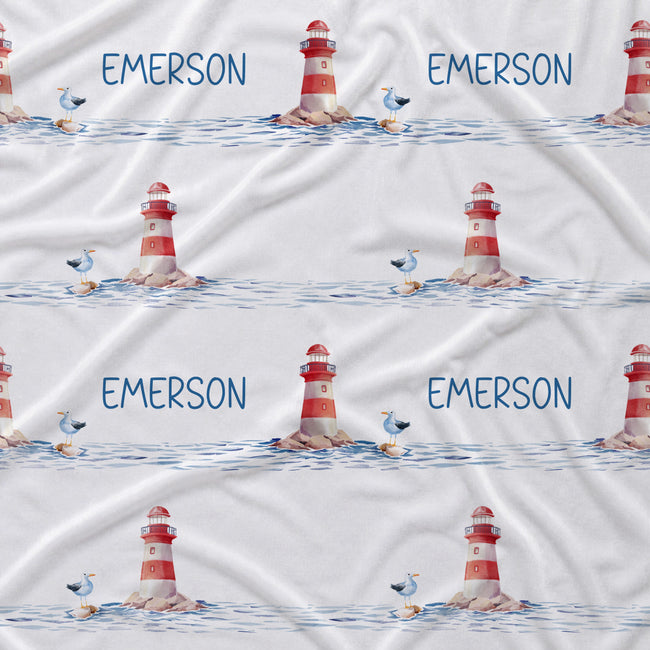 White fabric with a repeating nautical pattern featuring red-and-white lighthouses, blue water, small birds, and the name EMERSON printed in blue.