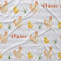 A close-up of a fabric surface with a repeating Easter-themed print featuring watercolor-style chickens, yellow chicks, green grass, and the name 'Maisie' in orange script on a white background.