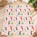 Personalized Tropical Bird Baby Girl Blanket. Colorful parrots, toucans, tropical leaves, and flowers surround a custom name on a soft pink background.