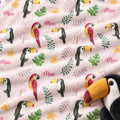 Personalized Tropical Bird Baby Girl Blanket. Colorful parrots, toucans, tropical leaves, and flowers surround a custom name on a soft pink background.