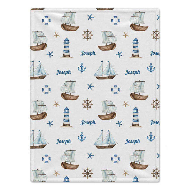 A rectangular blanket with a nautical-themed print featuring sailboats, lighthouses, anchors, life buoys, starfish, and ship wheels on an off-white background, personalized with the name 'Joseph' in blue script.