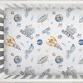 A crib mattress fitted sheet with a personalized space-themed print featuring watercolor-style rockets, satellites, planets, stars, and the text 'Jett James'.