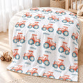 Personalized Tractor Baby Blanket. Coral watercolor tractors with blue wheels surround a custom name on a white background.
