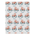 Personalized Tractor Baby Blanket. Coral watercolor tractors with blue wheels surround a custom name on a white background.