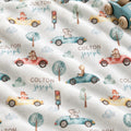 Personalized Animal Race Car Baby Blanket. Friendly animals drive colorful race cars among trees, clouds, and traffic lights around a custom name.