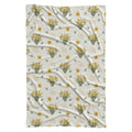 Ivory swaddle blanket with yellow daffodil clusters, green leaves, and the name Clara Mae in gold and sage green lettering.