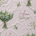 Pale blush fabric with white lily of the valley bouquets, green leaves, and the name Lillian Grace in rose and green lettering.