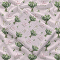 Pale blush swaddle blanket with white lily of the valley bouquets, green leaves, and the name Lillian Grace in rose and green.