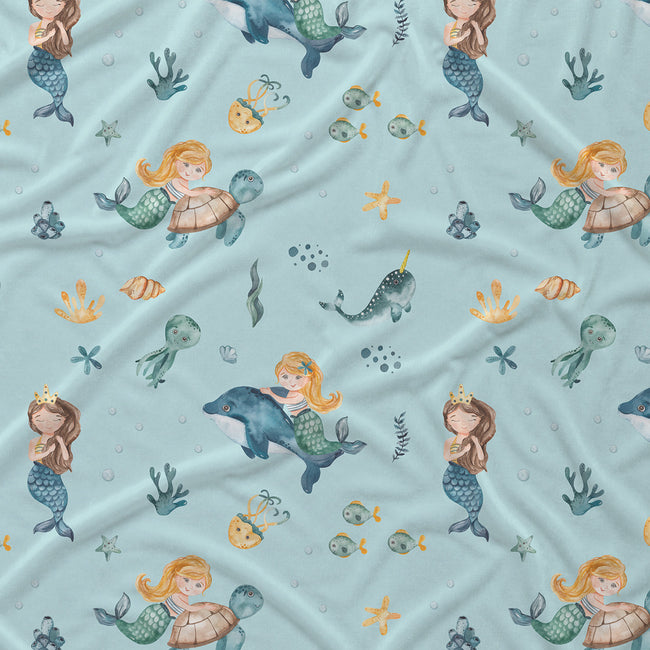 Light blue fabric with a repeating mermaid and sea life print, including mermaids with turtles, dolphins, fish, starfish, and sea plants.