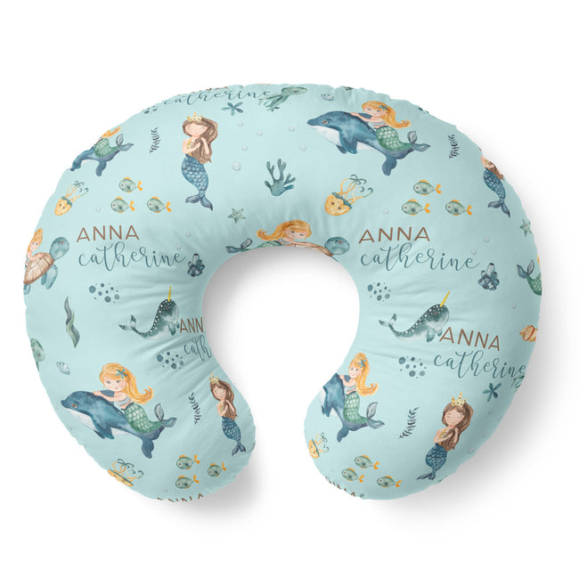 A U-shaped nursing pillow with a light blue mermaid and dolphin pattern, featuring the personalized name 'ANNA catherine' in script, shown on a white background.