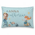 A personalized rectangular throw pillow featuring a light blue mermaid-themed design with two watercolor mermaids, sea turtles, starfish, and the names 'ANNA' and 'catherine' in brown and teal lettering.