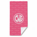 A pink beach towel with a repeating white 'CAROLINE' pattern and a large white circular monogram reading 'CWG'