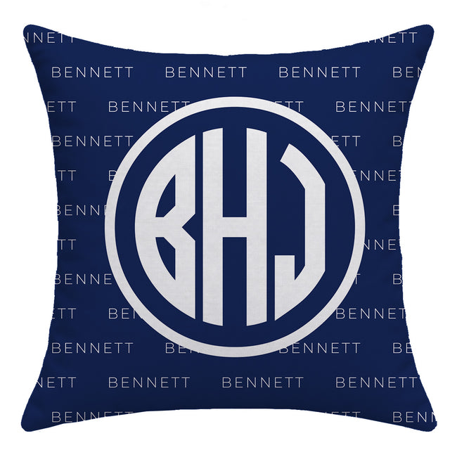 A square navy blue throw pillow featuring a large white circular monogram with the letters B, H, and J in the center. The background of the pillow has a repeating light gray 'Bennett' brand name pattern.