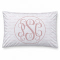 A pillowcase featuring a light pink monogrammed design with an interlocking monogram in the center, surrounded by a thin circular line, and a repeating 'PALMER' pattern in the background.