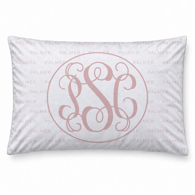 A pillowcase featuring a light pink monogrammed design with an interlocking monogram in the center, surrounded by a thin circular line, and a repeating 'PALMER' pattern in the background.