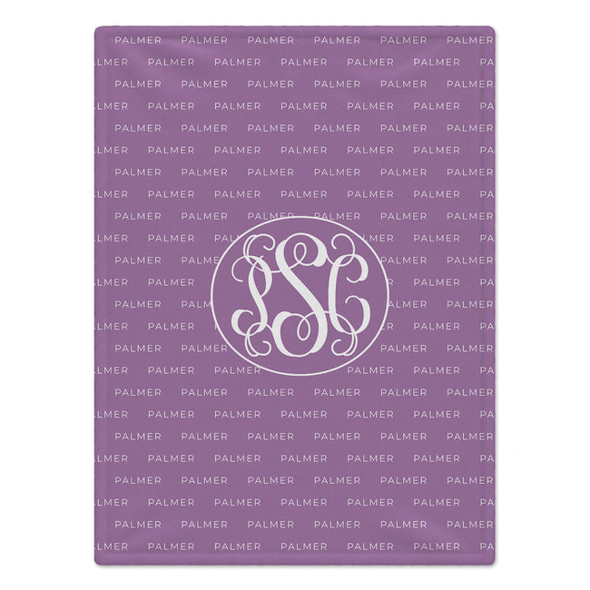 A square personalized monogrammed blanket in lavender purple with a repeating 'PALMER' pattern and a central white monogram circle containing 'P, 'S', and 'C'.