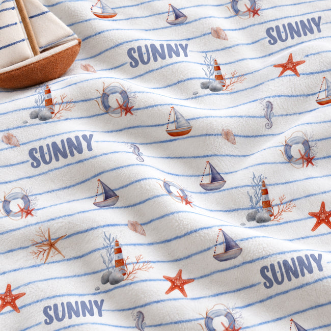Personalized Nautical Stripe Baby Boy Blanket. Sailboats, lighthouses, starfish, and seahorses surround a custom name over soft blue stripes.