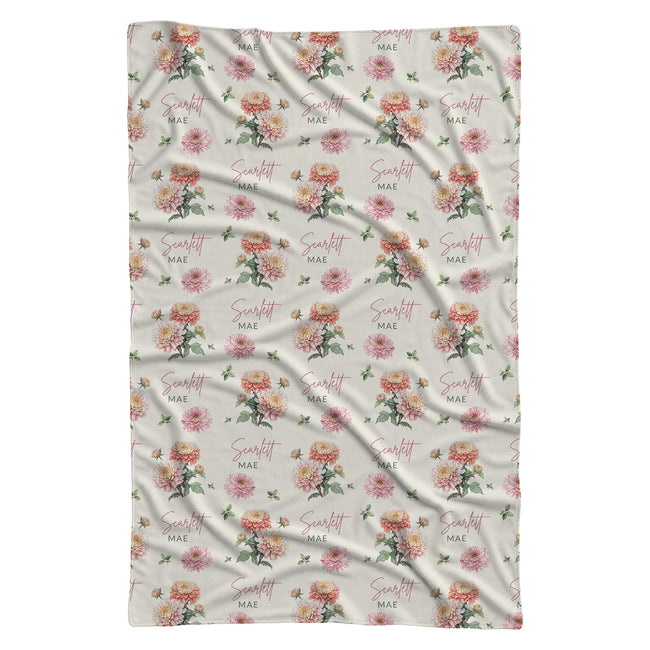 Ivory swaddle blanket with peach and pink chrysanthemums, green foliage, and the name Scarlett Mae in rose and green lettering.