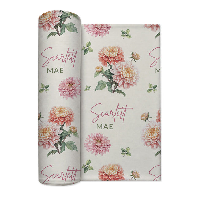 Ivory swaddle blanket with peach and pink chrysanthemums, green foliage, and the name Scarlett Mae in rose and green lettering.