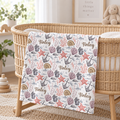 A personalized baby blanket with an ocean-themed pattern of shells, starfish, coral, and anchors, printed with the name 'Finley' in brown script, draped over a wicker bassinet in a softly lit nursery.