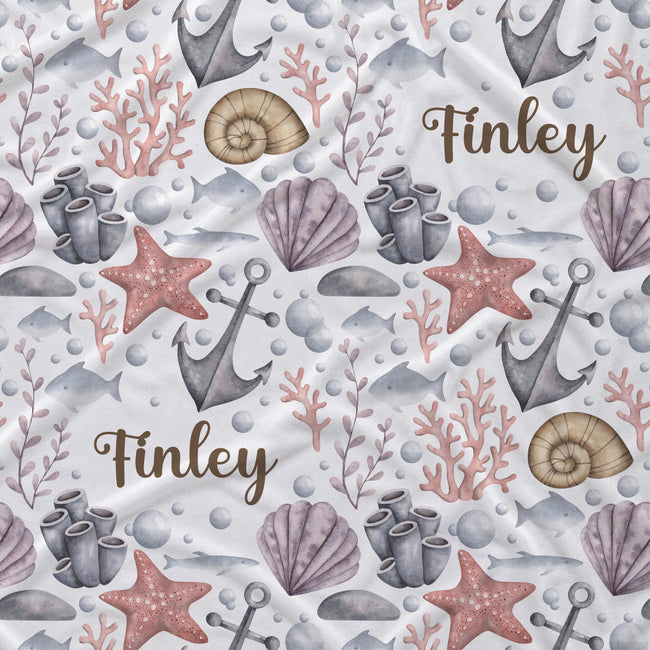 A repeating nautical pattern on a white background featuring gray anchors, purple seashells, pink starfish, coral, bubbles, and the name 'Finley' in brown script.