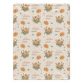 Cream blanket with golden-orange marigold clusters, scattered green leaves, and the name Autumn Grace in orange and green.