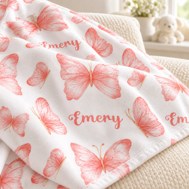 Personalized Peach Butterfly Baby Girl Blanket. Delicate peach-pink watercolor butterflies surround a custom name in a light, graceful design.