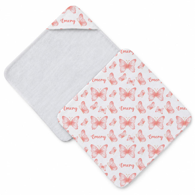 White hooded towel featuring peach and coral butterflies in different sizes and the name Emery in coordinating script.