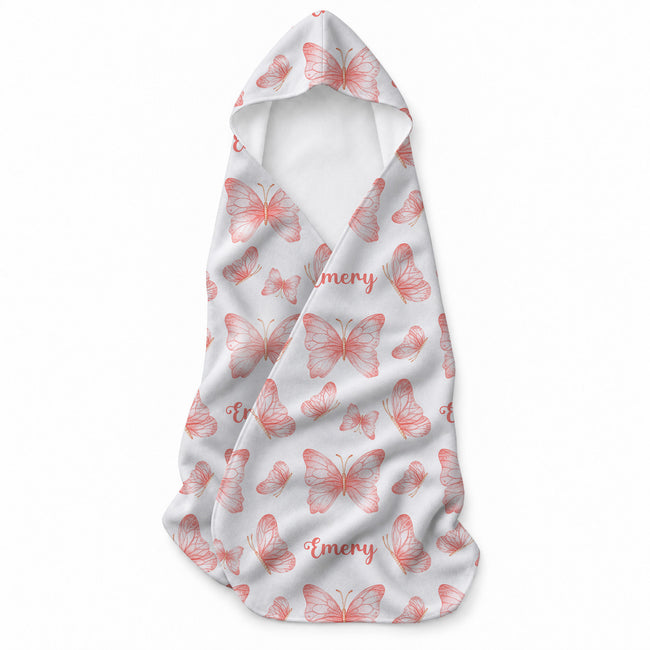 White hooded towel featuring peach and coral butterflies in different sizes and the name Emery in coordinating script.