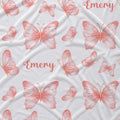 White fabric with a repeating pattern of pink watercolor butterflies and the name 'Emery' in pink script.