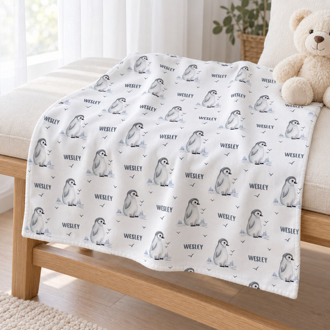 Personalized Penguin Baby Blanket. Sweet baby penguins, icy landscape accents, and little flying birds surround a custom name on a white background.