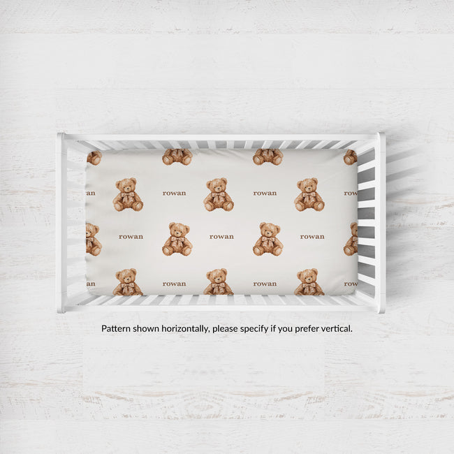 Teddy bear crib sheet personalized with Rowan in a white crib; note states the pattern is horizontal, with vertical available by request.
