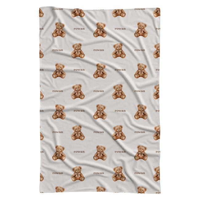 Full view of a personalized teddy bear swaddle blanket with repeating watercolor bears and the name Rowan on a white background.