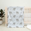 Little Elephant baby blanket personalized with Cooper, draped over a natural wood crib in a neutral nursery.