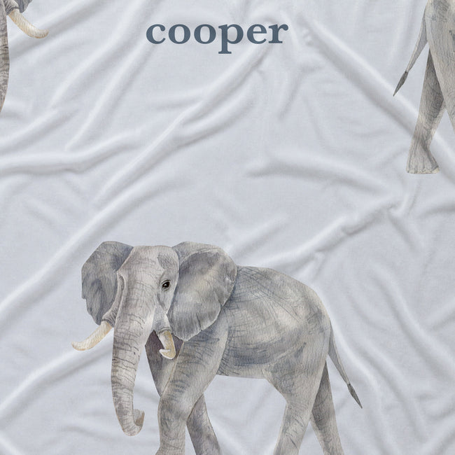 Close-up of Little Elephant fabric showing a detailed gray watercolor elephant and Cooper in slate blue lettering on pale blue.
