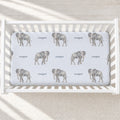 Overhead view of Little Elephant personalized crib sheet with gray watercolor elephants and the name Cooper on pale blue in a white crib.