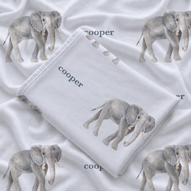 Folded Little Elephant personalized swaddle blanket showing a gray watercolor elephant and Cooper in slate blue lettering.