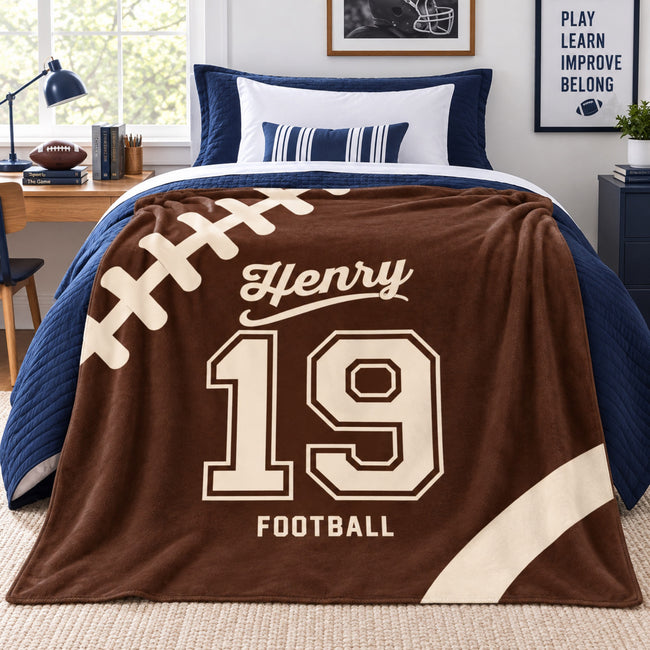 Personalized Henry number 19 football blanket draped over navy bedding in a football-themed bedroom.