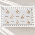Overhead view of Little Giraffe personalized crib sheet with watercolor giraffe pairs and the name Emerson in a white crib.
