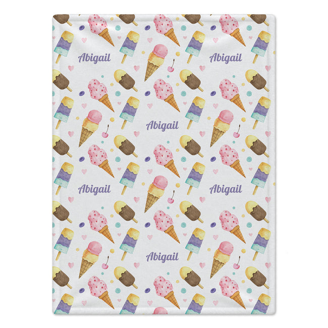 A blanket, featuring a repeating pattern of watercolor ice cream cones, popsicles, small hearts, and the name 'Abigail' in purple script. The background of the pattern is white, and the fabric is shown flat against a clean white background.