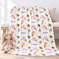 Personalized watercolor ice cream blanket with Abigail in purple script, draped over a light wood bench with a pink cloth doll resting on the edge.