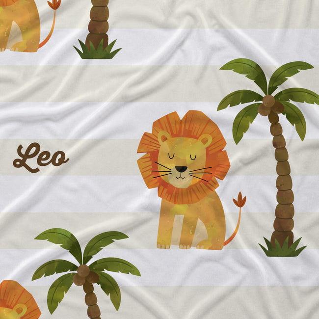 Close-up of Little Lion fabric showing a golden lion with an orange mane, a green palm tree, and Leo in brown script on cream and white stripes.