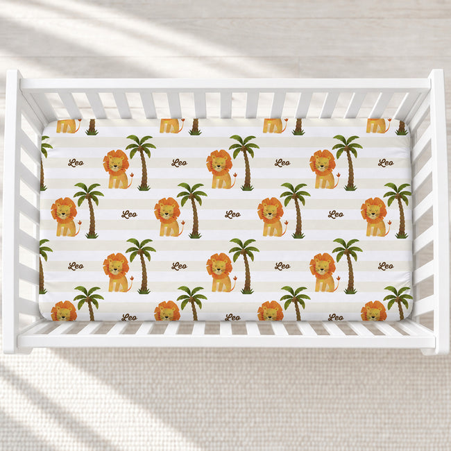 Little Lion personalized crib sheet with golden lions, green palms, cream and white stripes, and the name Leo in a white crib.