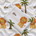 Folded Little Lion swaddle blanket showing Leo in brown script beside a golden lion and green palms on cream and white stripes.