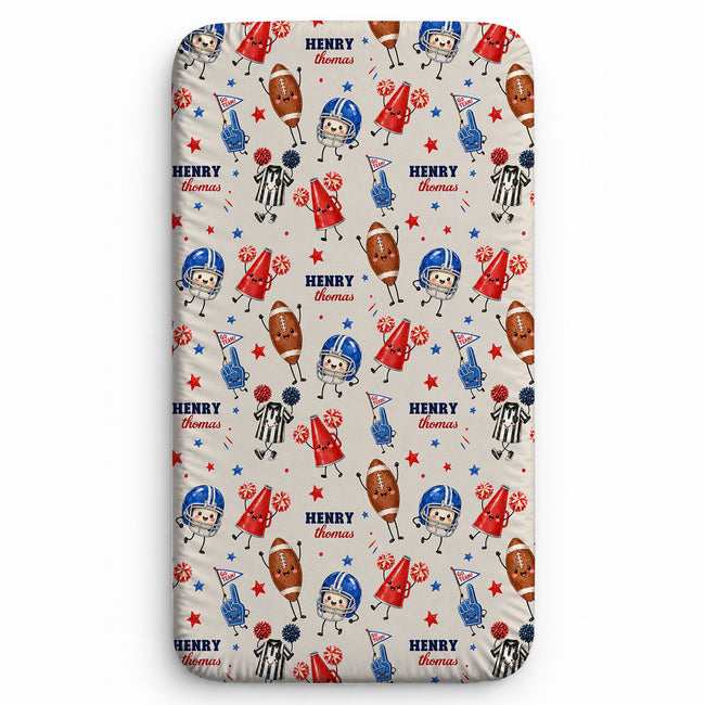 A fitted sheet with a custom football-themed cartoon pattern. The design features a beige background with repeating illustrations of football players, helmets, footballs, referees, and stars in red, blue, and brown, with the name 'HENRY Thomas' printed in red and blue text.
