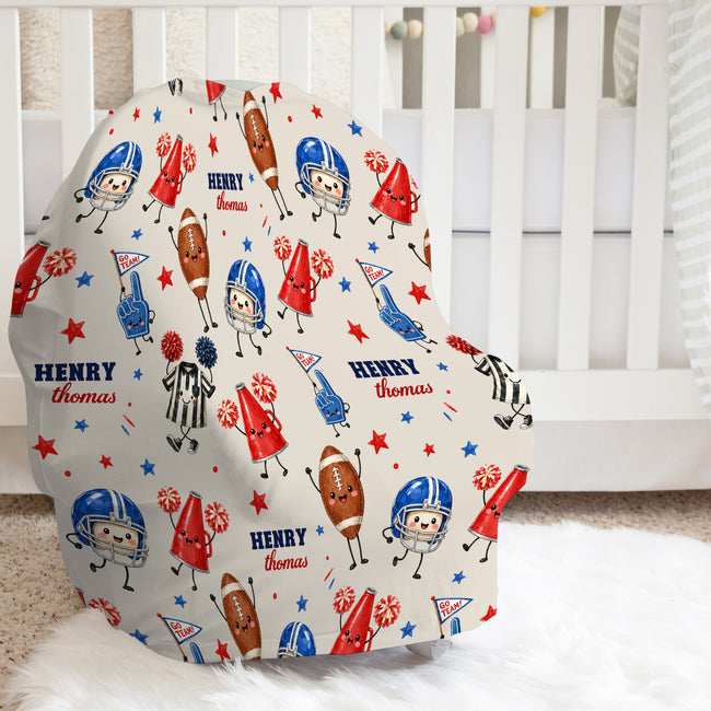 A baby car seat cover featuring a personalized football-themed print with cartoon players, referees, stars, and the name 'HENRY Thomas' on a cream background, styled in a nursery setting.
