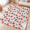 A personalized fleece blanket with a football-themed cartoon pattern is spread out on a light wood floor in a child's bedroom. The blanket features a cream background with illustrations of football players, footballs, referees, stars, and the name 'HENRY' printed in blue.