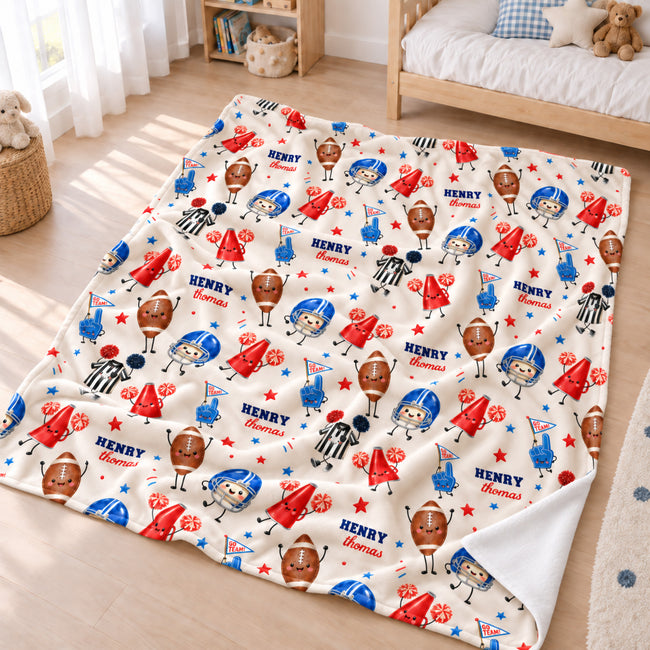 A personalized fleece blanket with a football-themed cartoon pattern is spread out on a light wood floor in a child's bedroom. The blanket features a cream background with illustrations of football players, footballs, referees, stars, and the name 'HENRY' printed in blue.